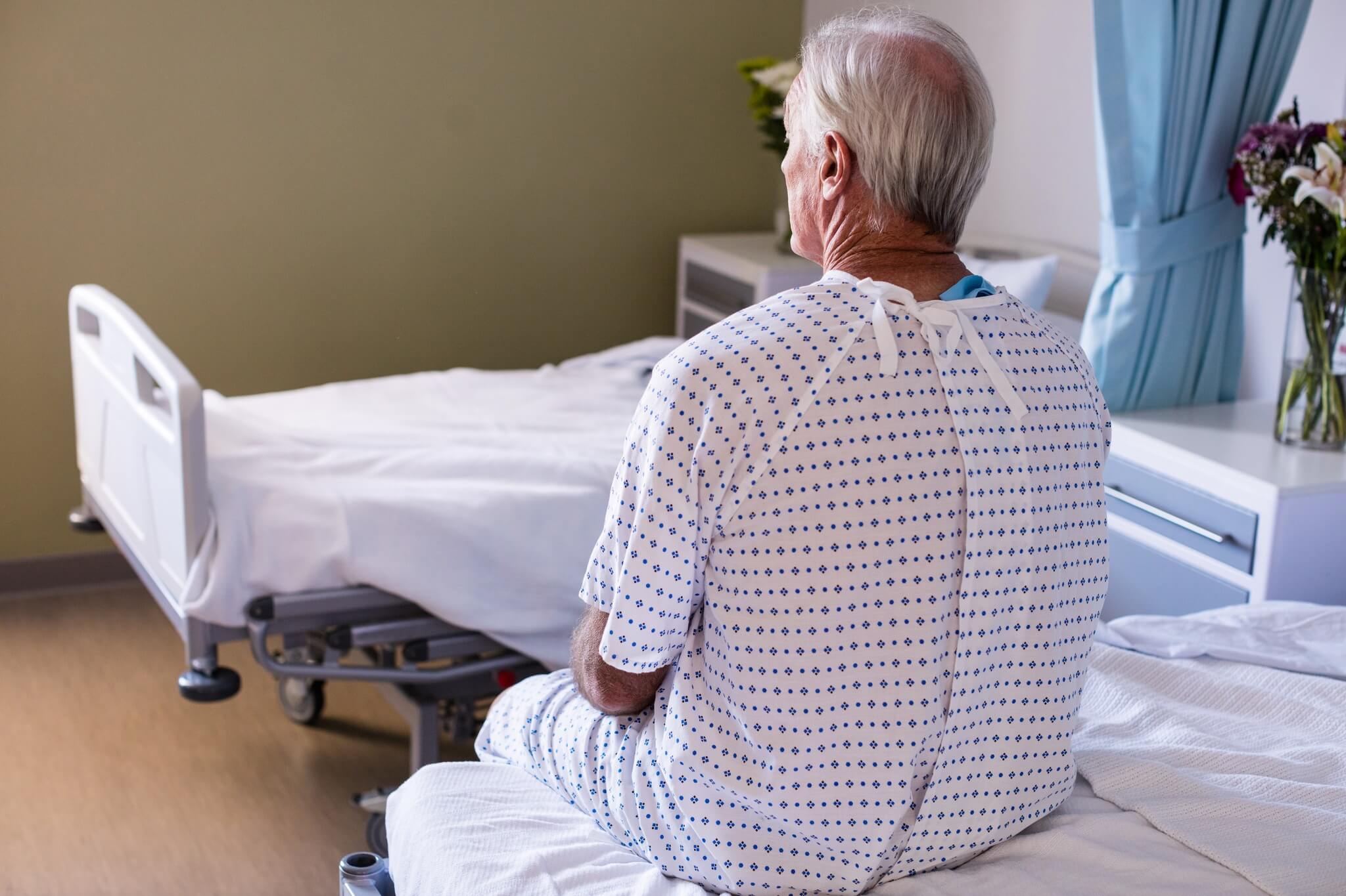 Man sitting on bed in surgery clothes