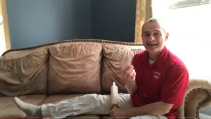 Tony Sitting on Couch Demonstrating Rolling Pin Massage for Knee Pain